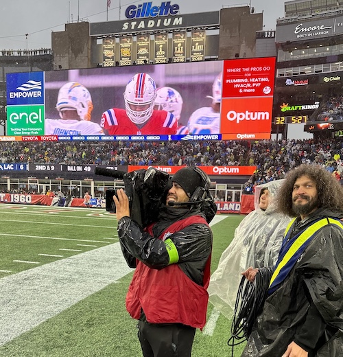 Camera operator Rafael Figuereo Jr. and utility technician Angel Figueroa work in the rain at Gillette Stadium to provide the best viewing experience for NFL fans.